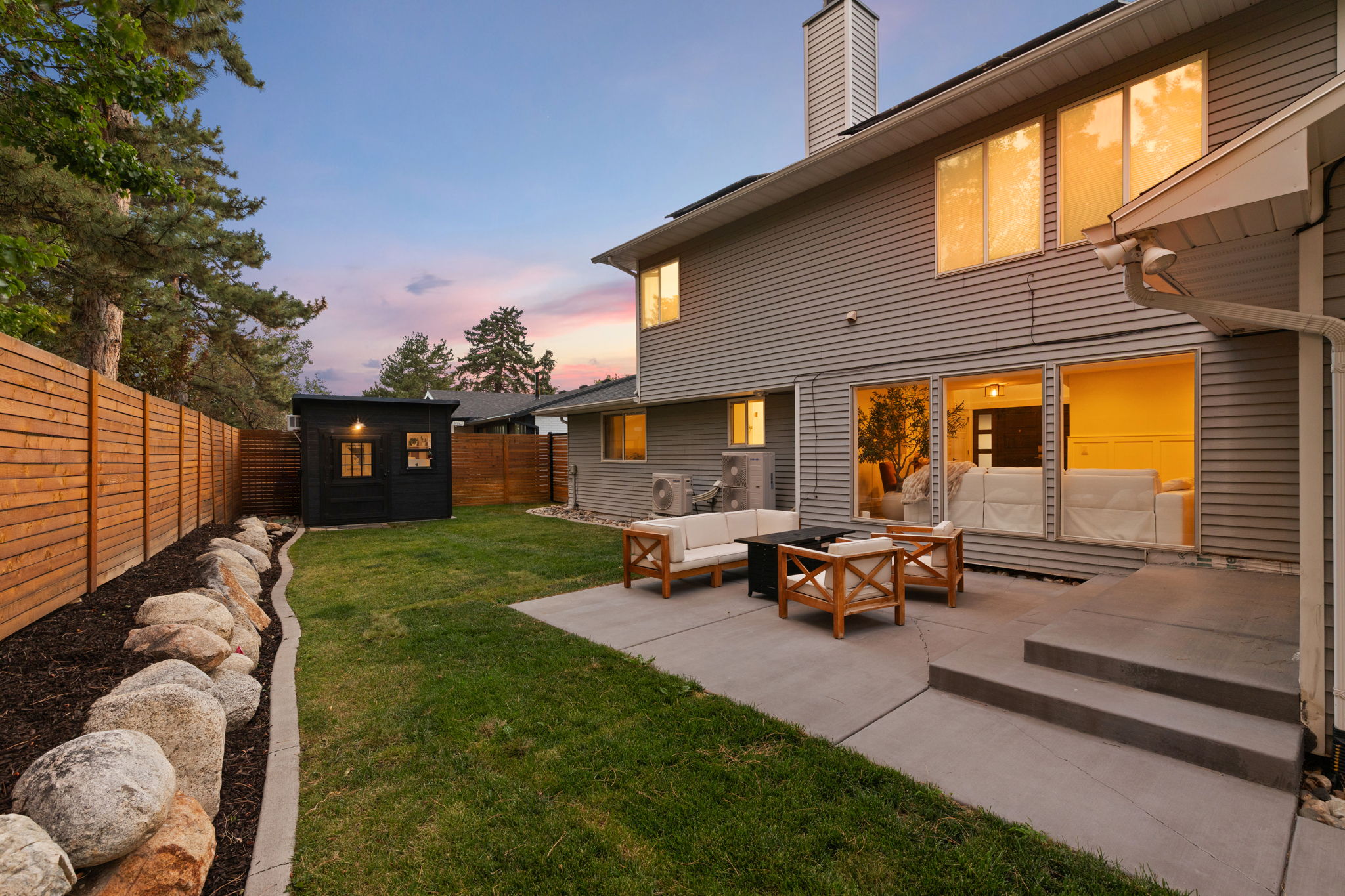 Expansive backyard featuring a manicured lawn, a modern black shed with windows, and a horizontal wood privacy fence