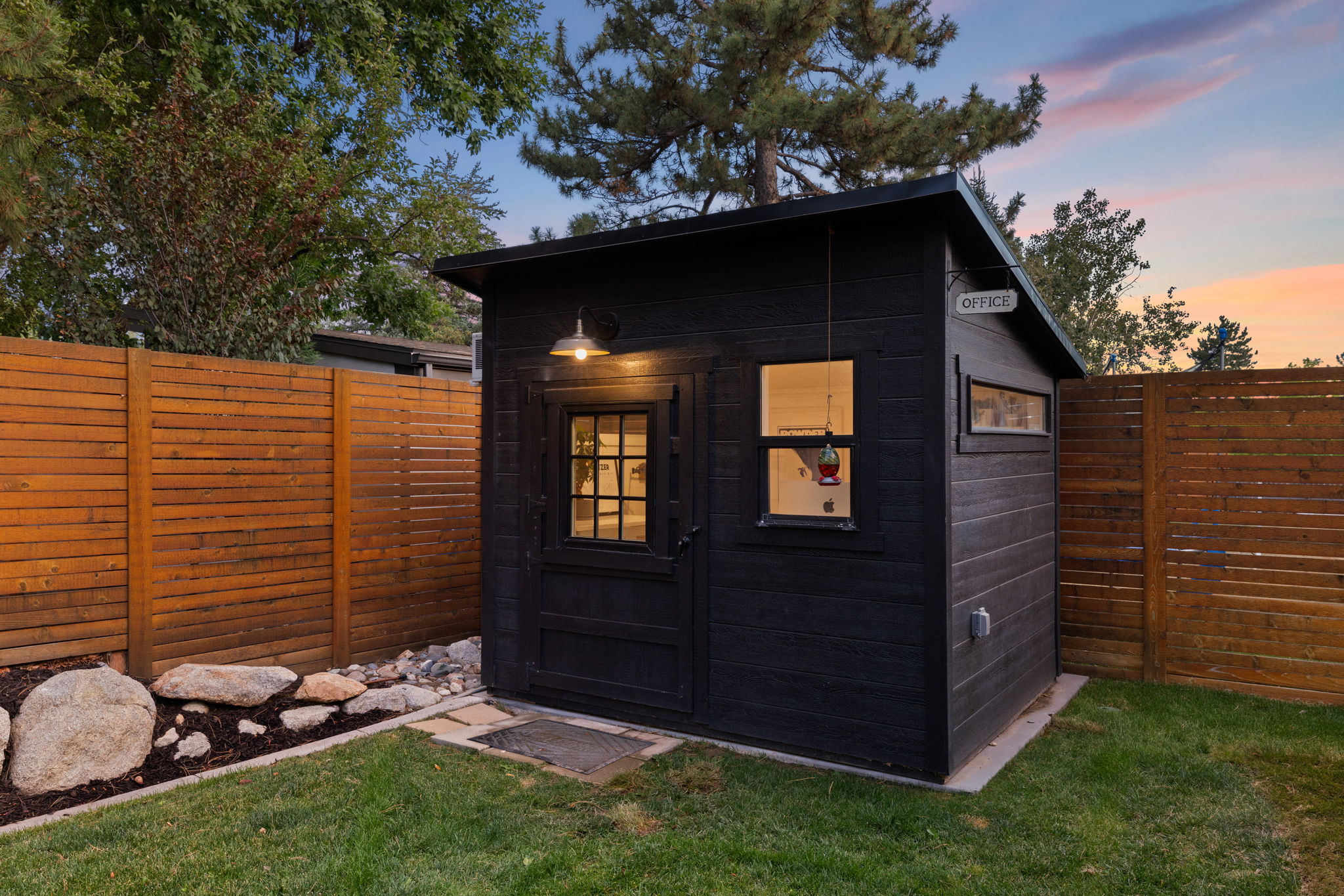 Modern black wood-paneled outbuilding featuring a pitched roof and a functional window with grid detailing