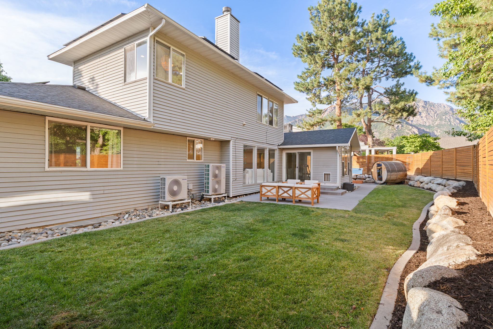 Expansive backyard featuring a manicured lawn, a concrete patio, a privacy fence, and a barrel sauna