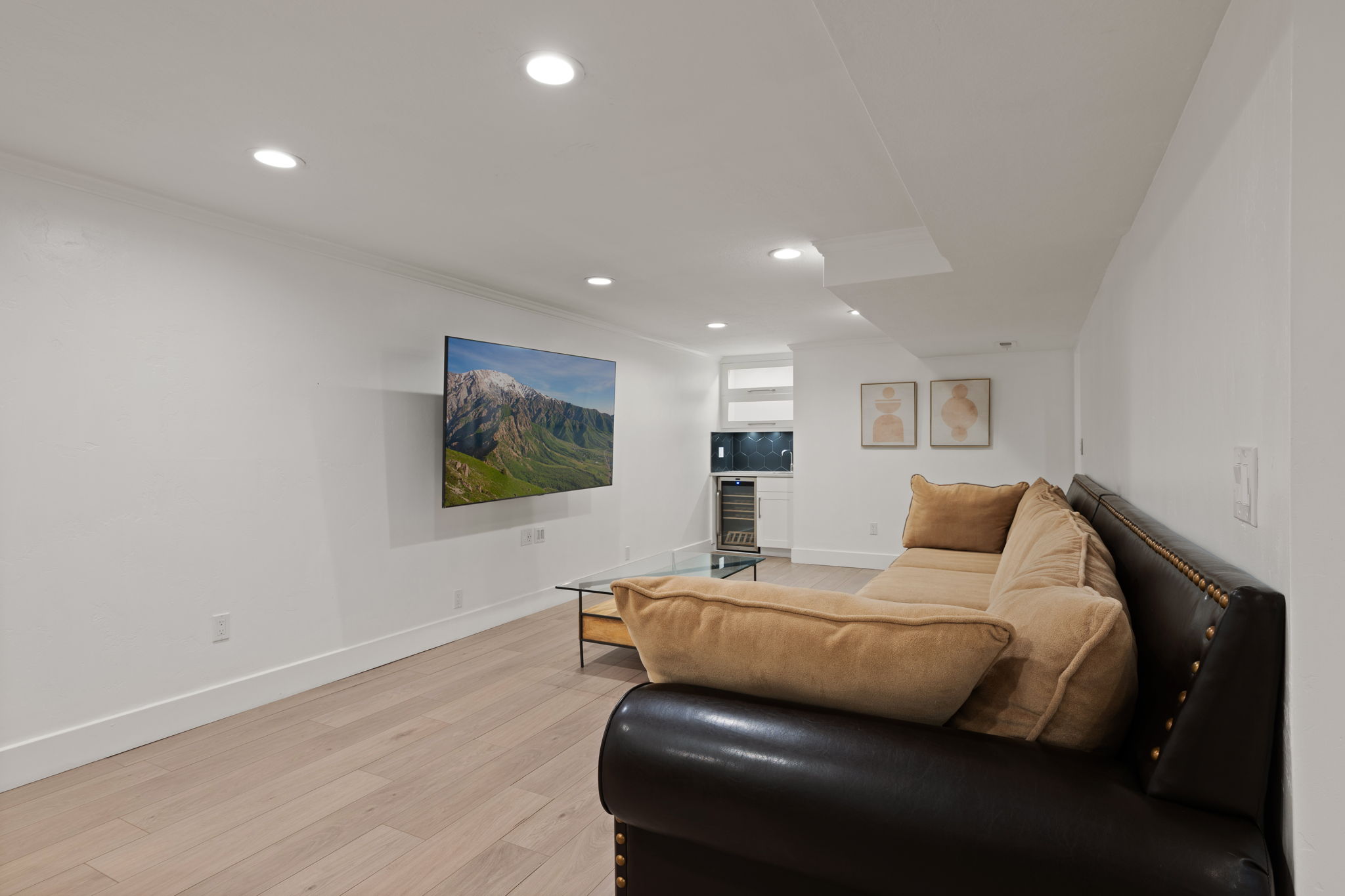 Entertainment area featuring a wall-mounted television, recessed lighting, and light wood-finish flooring