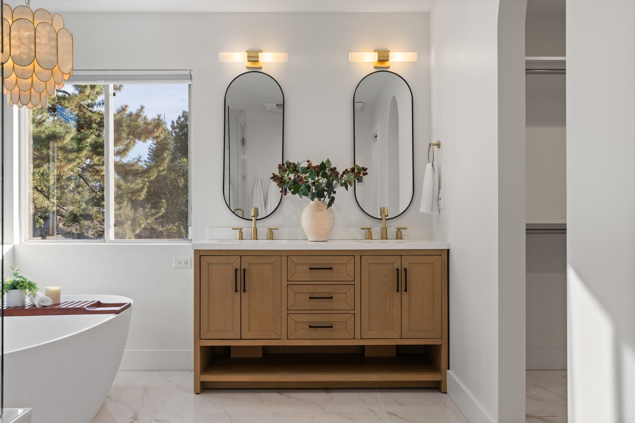 Double vanity with wood-finish cabinetry, white stone countertop, and brass-finish fixtures