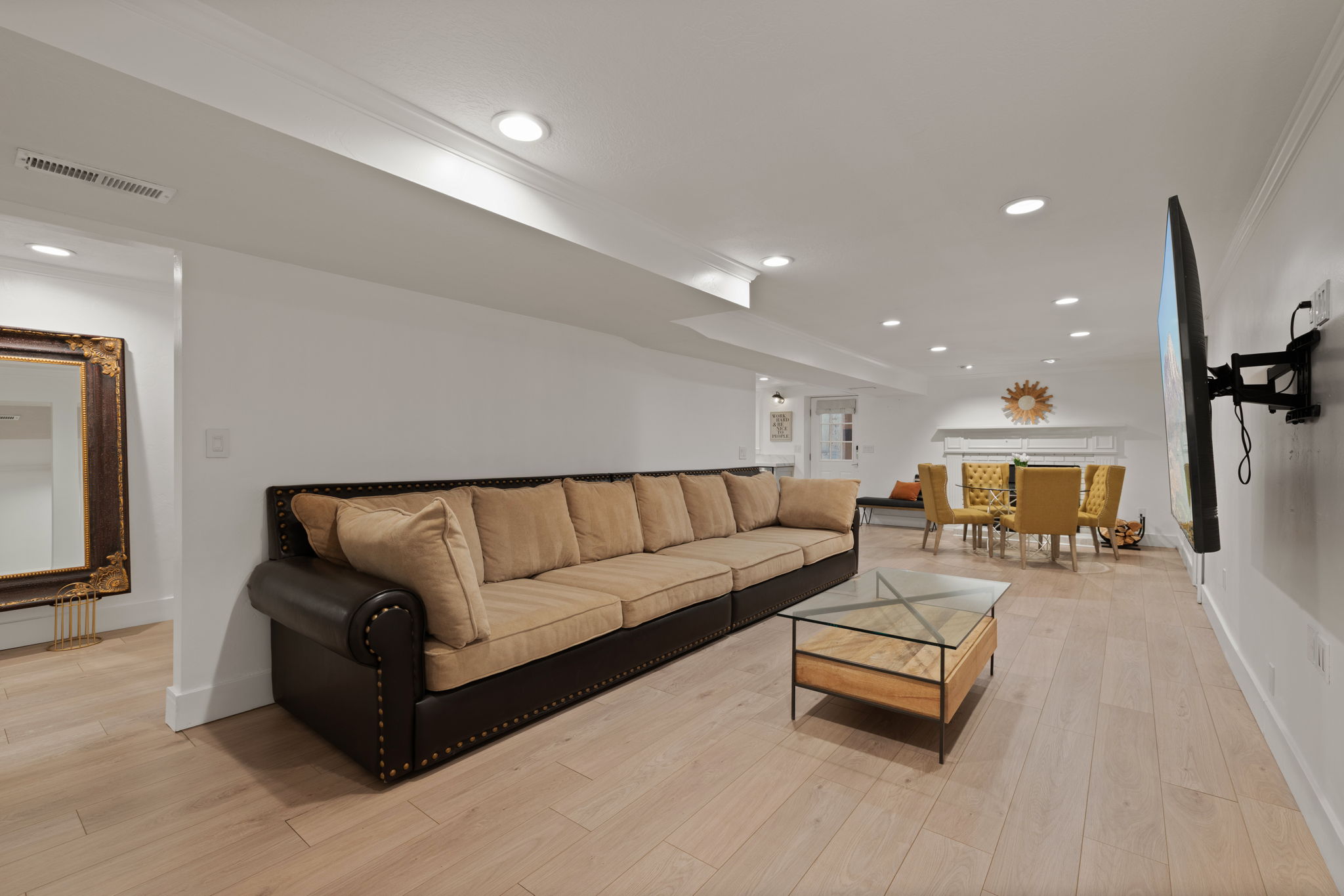 Open-concept living area featuring light wood-finish flooring, recessed lighting, and crisp white walls