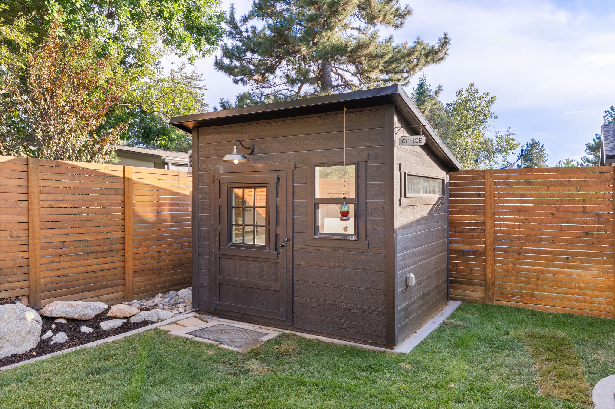 Freestanding backyard structure featuring dark wood-finish siding, a gabled roof, and multiple windows providing natural light