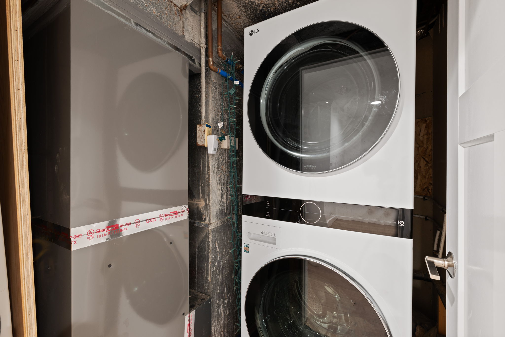 Laundry area featuring a stacked washer and dryer unit, modern white appliances, and a solid white door