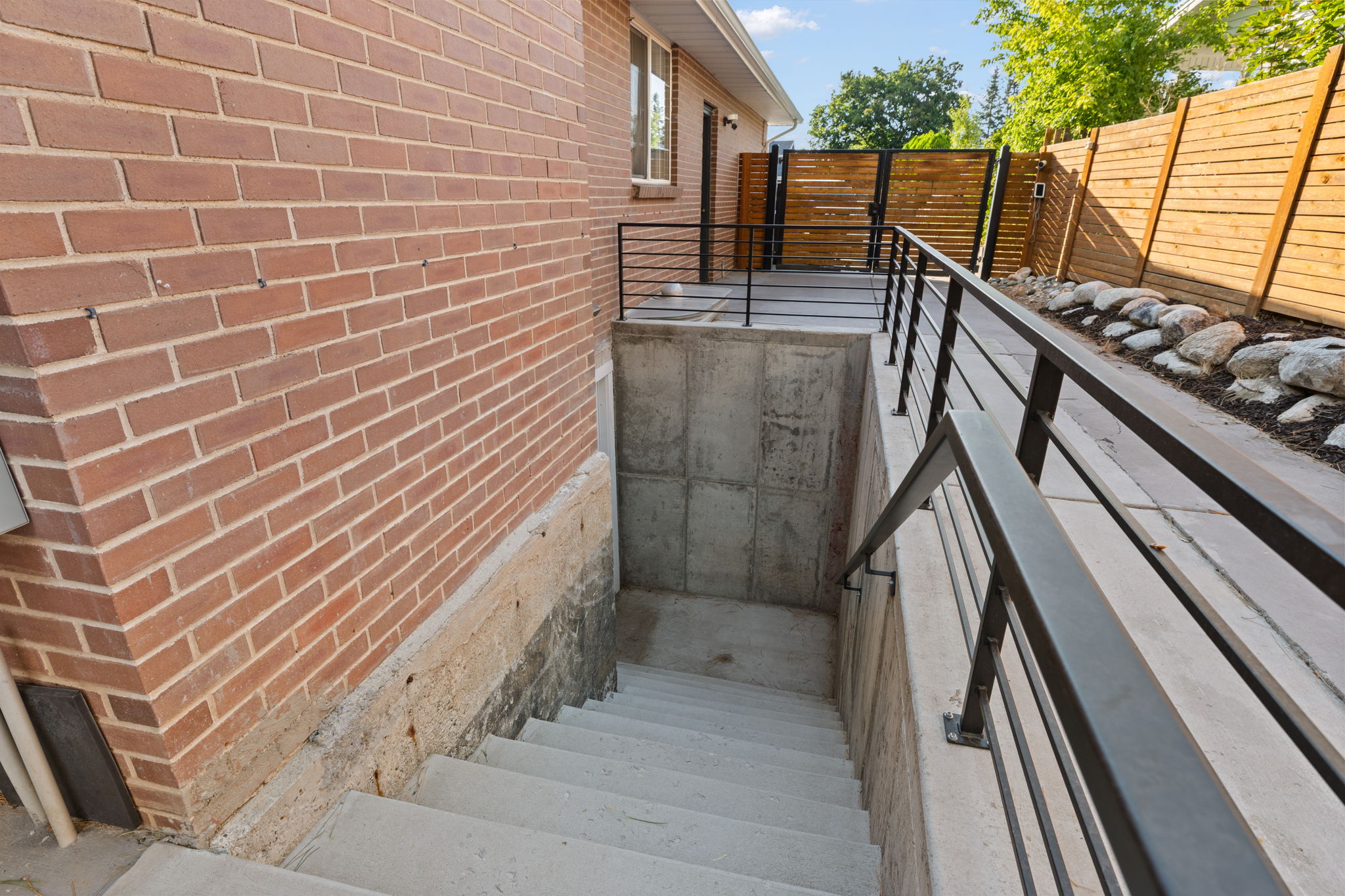Concrete stairwell with black metal handrails providing access to a lower level