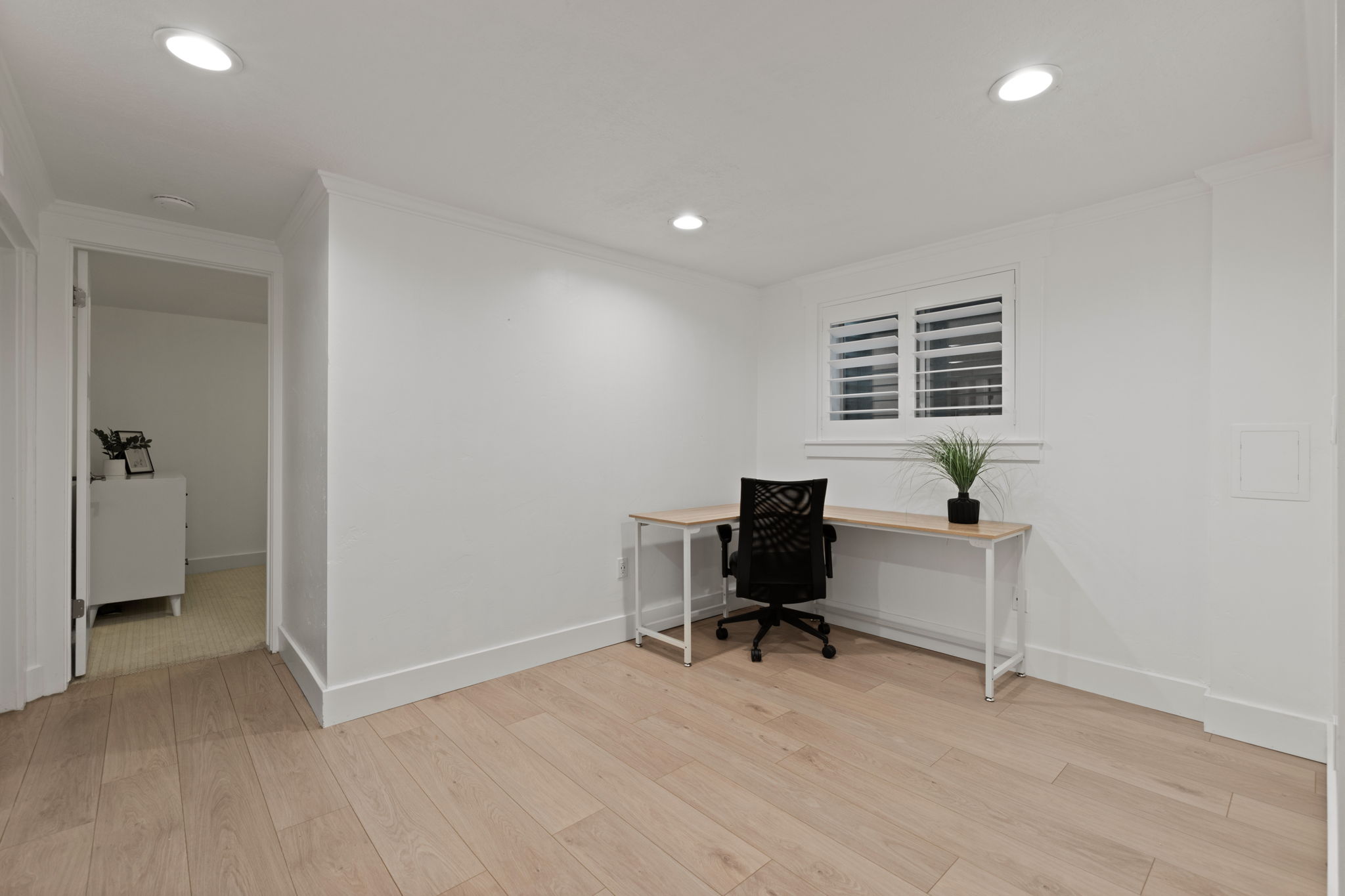 Room featuring light wood-finish flooring, recessed lighting, and a window with white louvered shutters