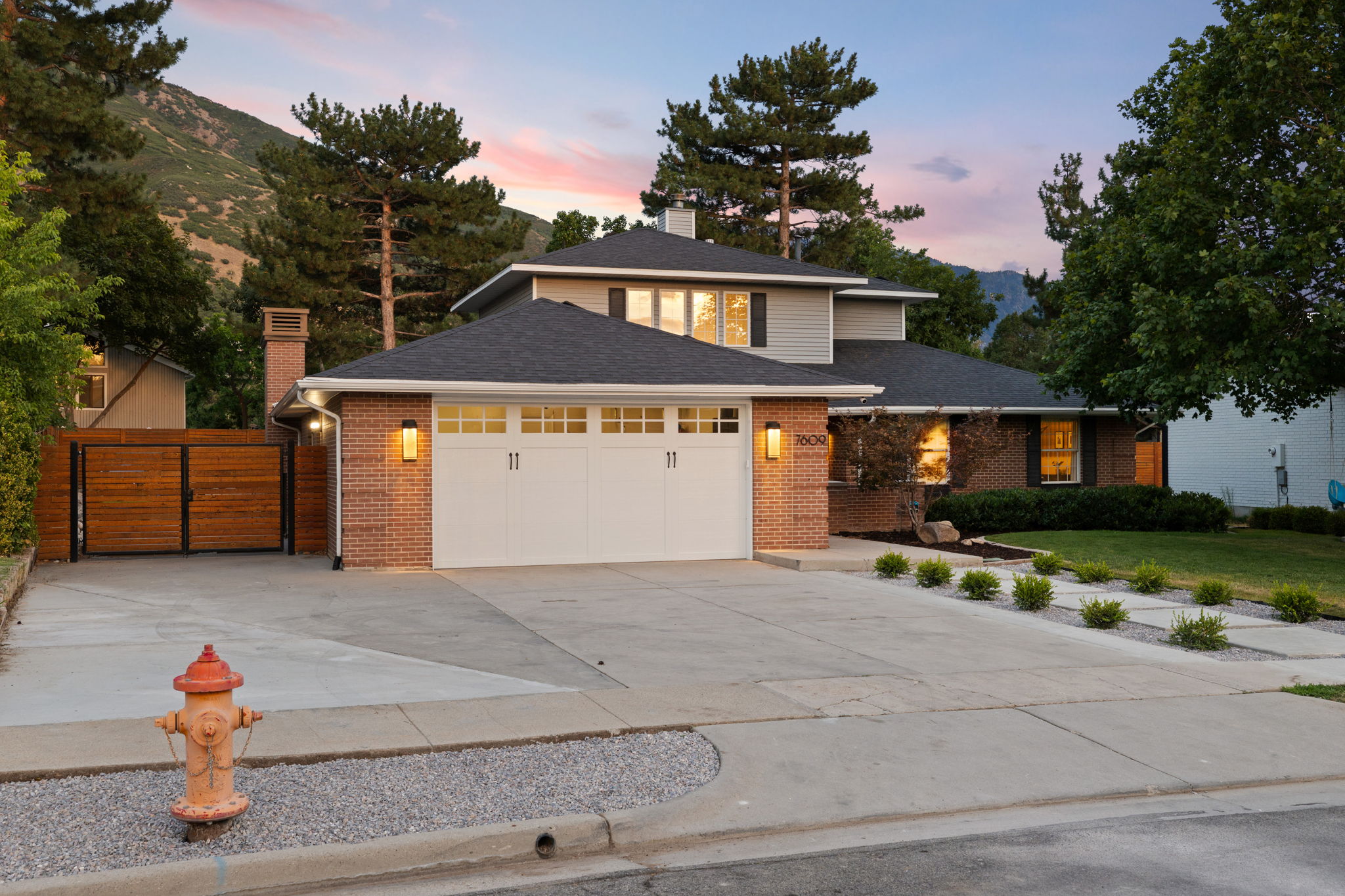 Contemporary two-story residence featuring a two-car garage with overhead lighting, brick and siding exterior, and a manicured front lawn