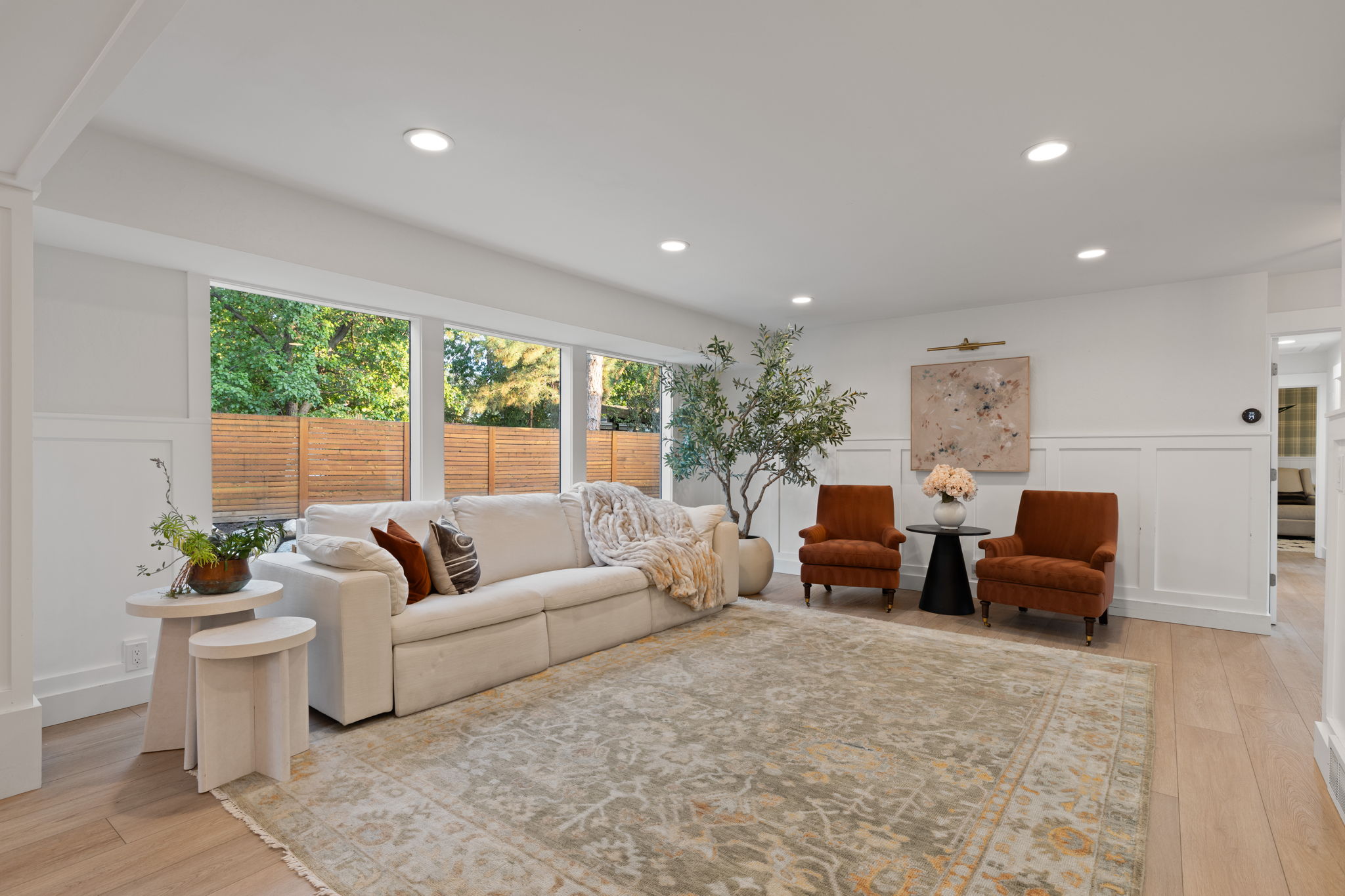 Spacious living area featuring large windows, light wood-finish flooring, recessed lighting, and wainscoting