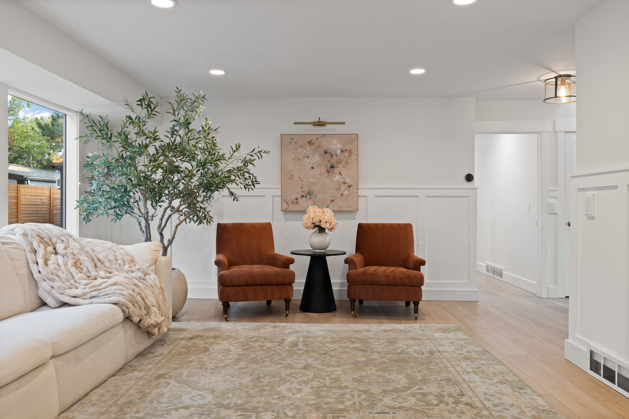 Open-concept living area featuring light wood-finish flooring, recessed lighting, and crisp white board and batten wall detailing
