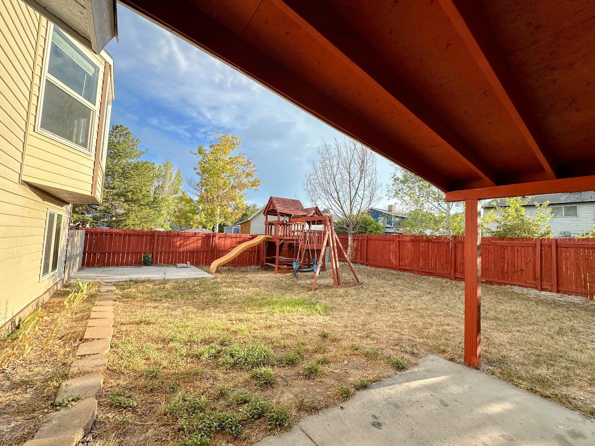 Expansive backyard featuring a stained wood privacy fence and mature trees
