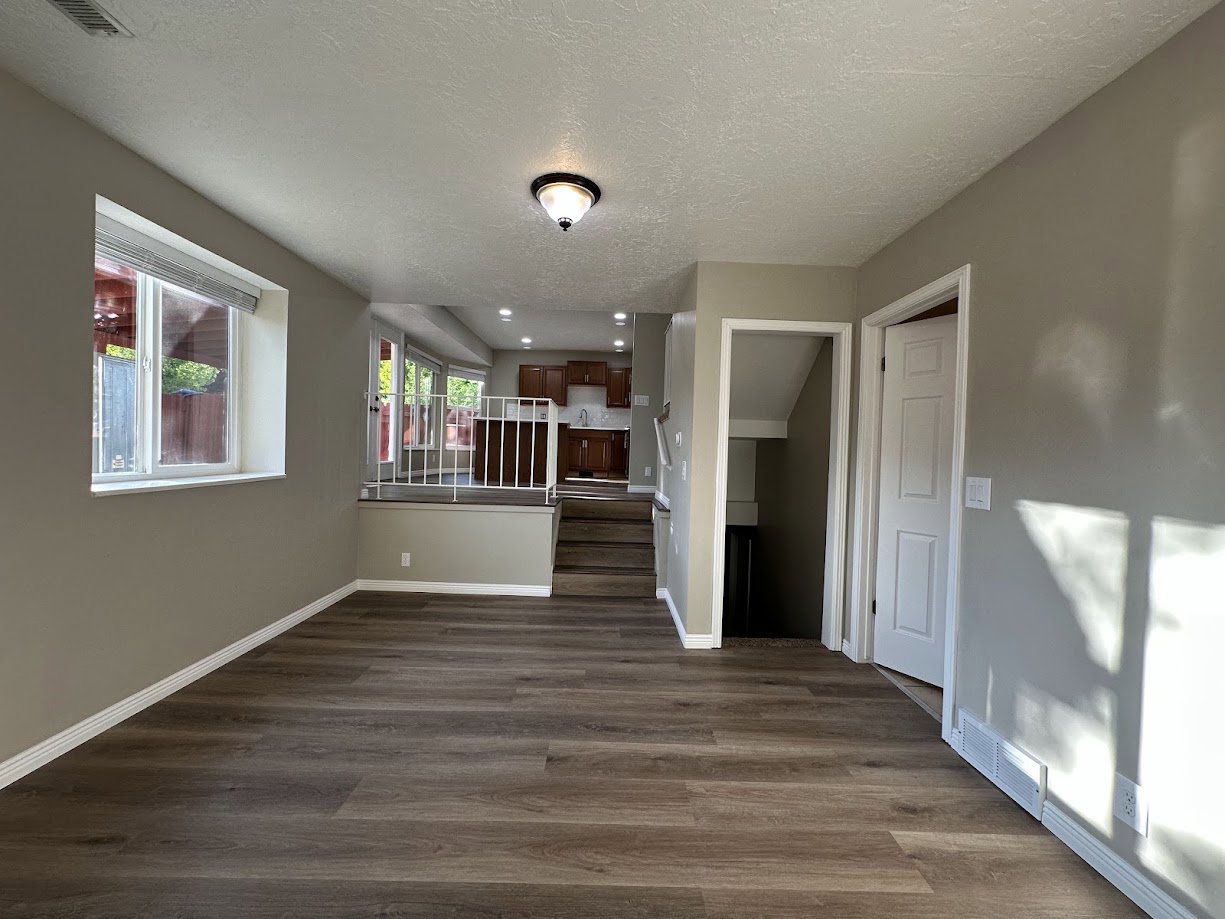 Spacious room with wood-finish flooring, neutral-toned walls, and white baseboards