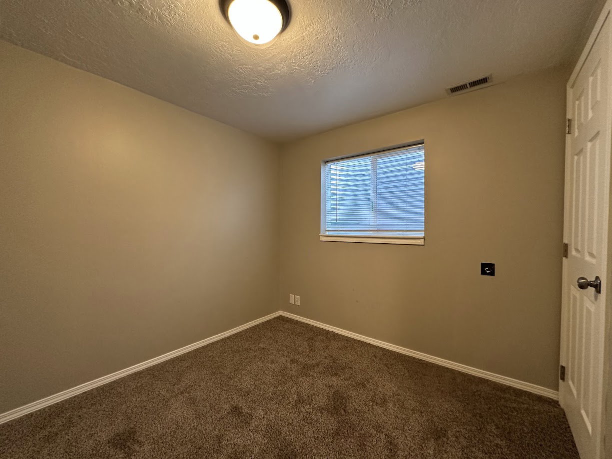 Room featuring neutral wall tones, brown carpet, and a window with blinds