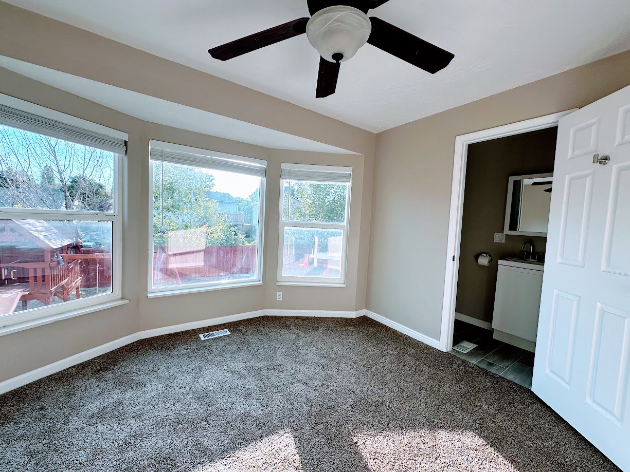 Carpeted room with a bay window design and a dark wood-finish ceiling fan
