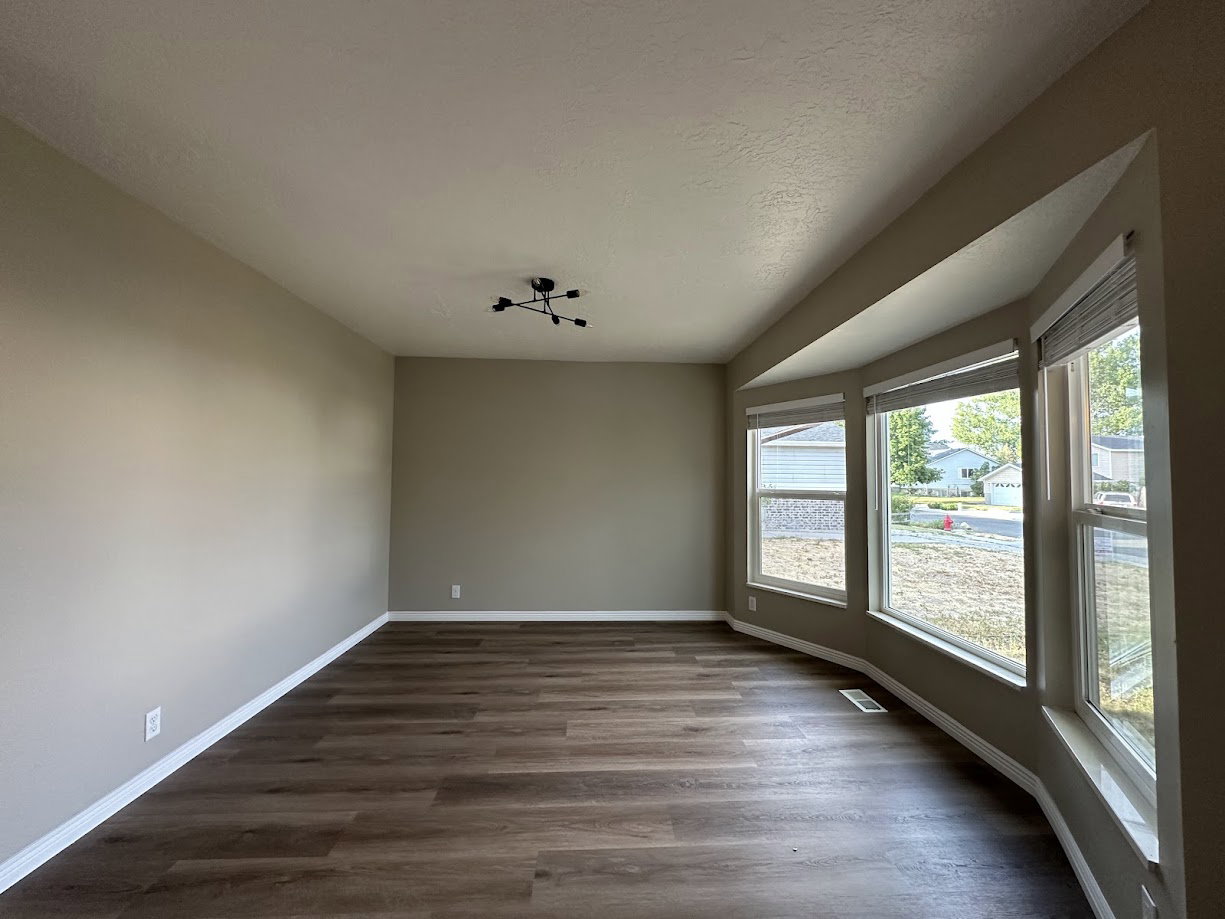 Bay window with multiple panes, wood-finish flooring, neutral wall tones, and a modern ceiling light fixture