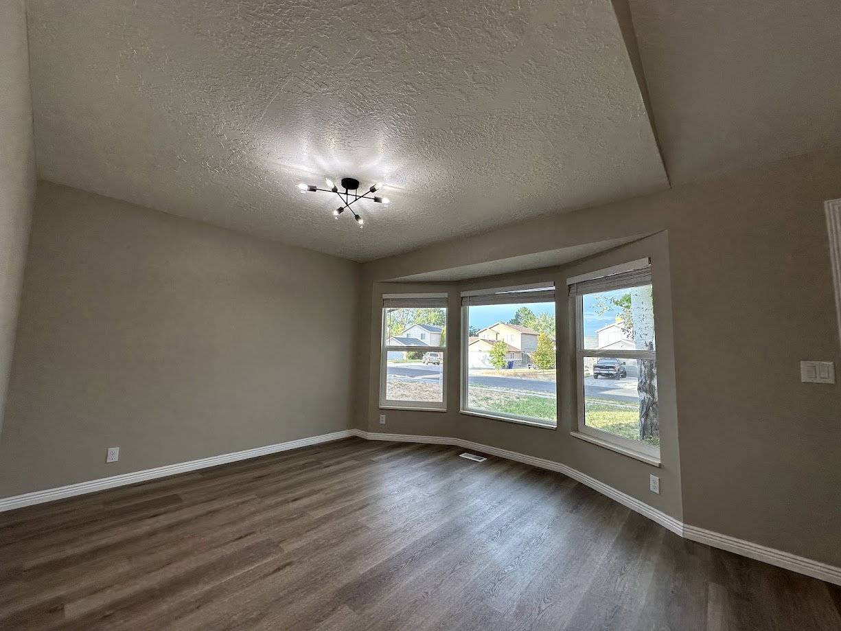 Spacious room featuring a vaulted ceiling and a modern ceiling light fixture