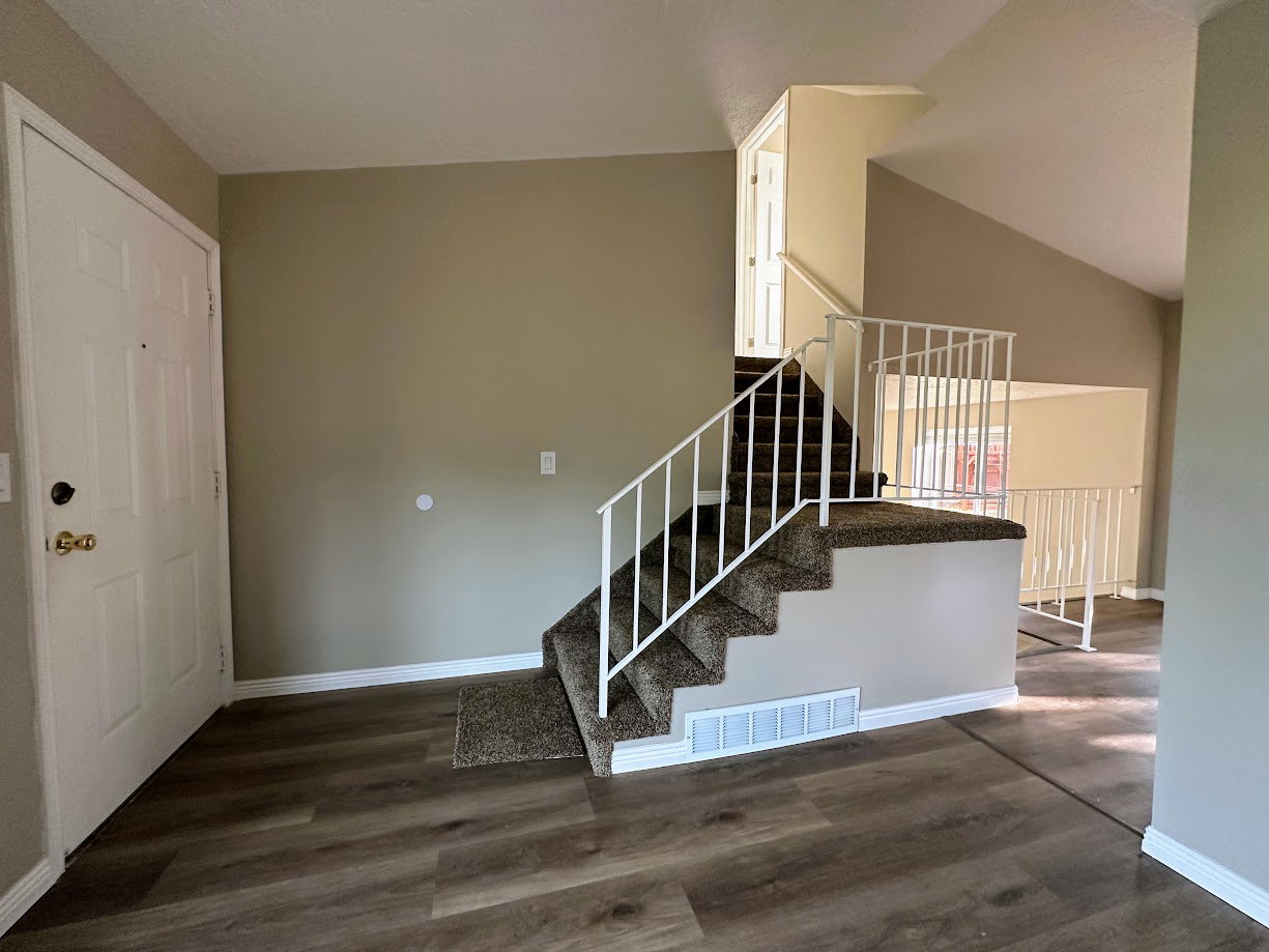 Foyer entry featuring a white panel door and wood-finish flooring
