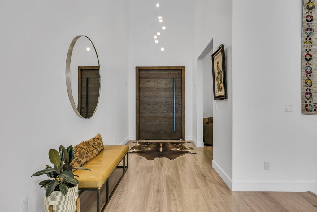 Vaulted entryway featuring wood-finish flooring, a contemporary dark wood door with a vertical pull handle, a high ceiling, and recessed lighting