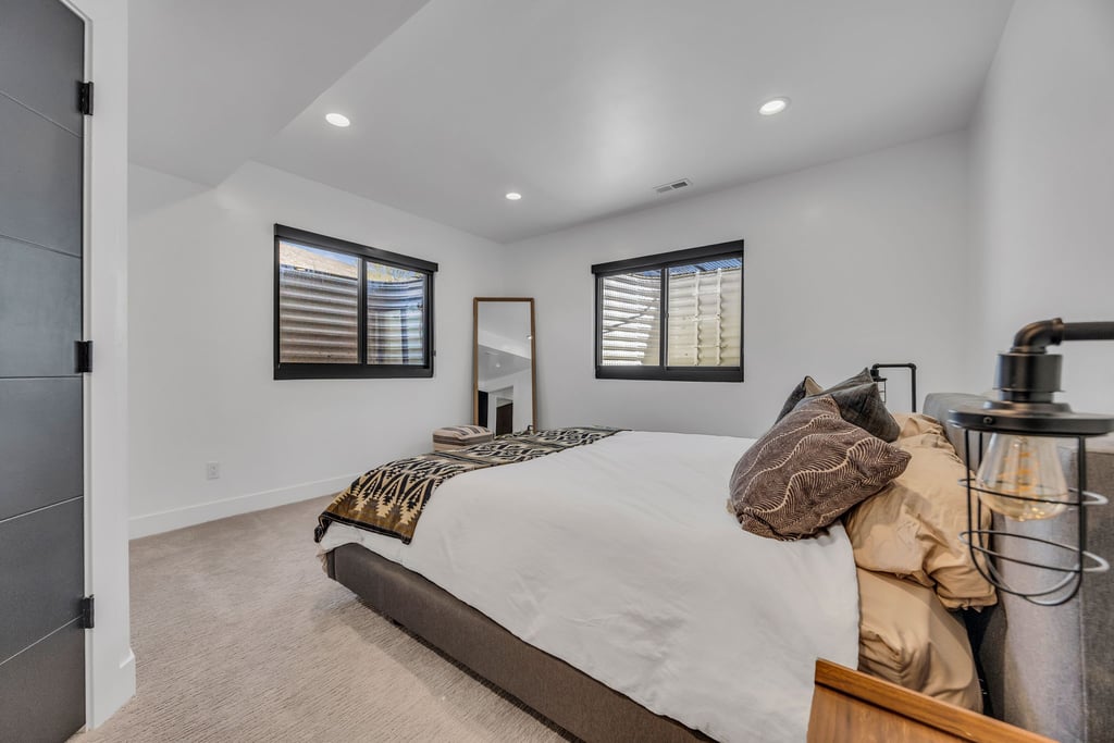 Bedroom featuring two windows with black trim, recessed ceiling lighting, and light-toned carpeting