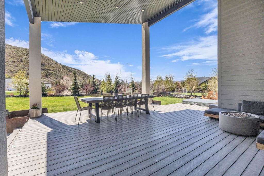 Expansive covered deck featuring composite decking, recessed lighting, and support columns