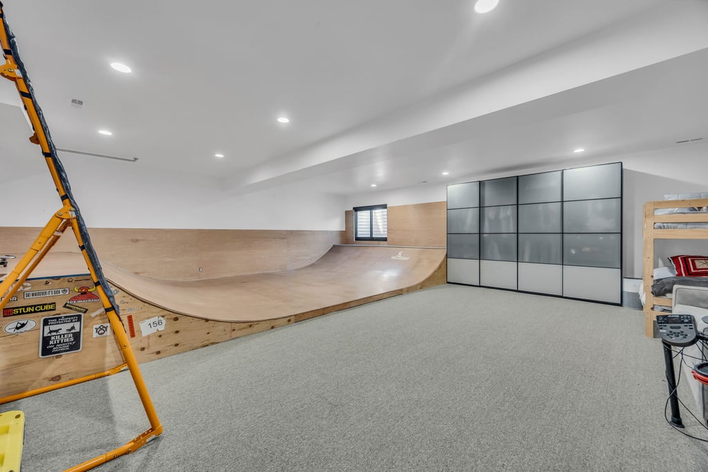 Recreation room featuring a built-in skate ramp, light gray carpet, recessed lighting, and a window with louvered shutters