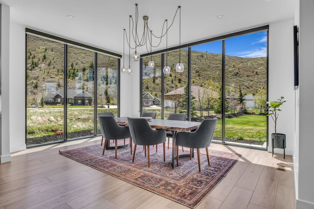 Dining area featuring expansive floor-to-ceiling windows, light wood-finish flooring, and a modern multi-pendant light fixture