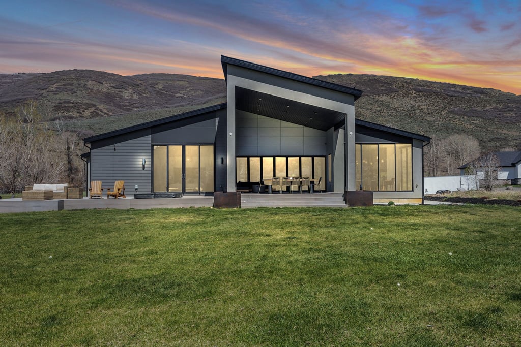 Contemporary architectural facade featuring a sloped roofline, dark siding, and extensive window walls