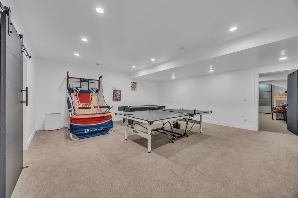 Spacious room featuring neutral carpet flooring, recessed lighting, white walls, and a modern barn door with black hardware