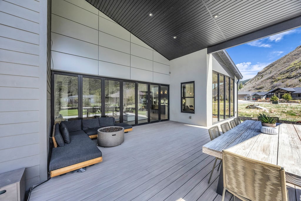 Expansive outdoor deck featuring wood-finish decking, a large folding glass door system, and a modern slatted ceiling