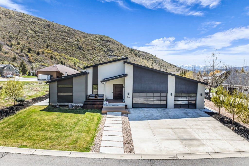 Modern architectural residence with a striking sloped roofline, featuring a two-car garage with contemporary glass panel doors