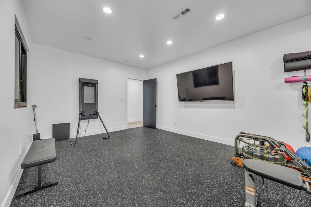 Spacious room featuring speckled rubber flooring and recessed lighting
