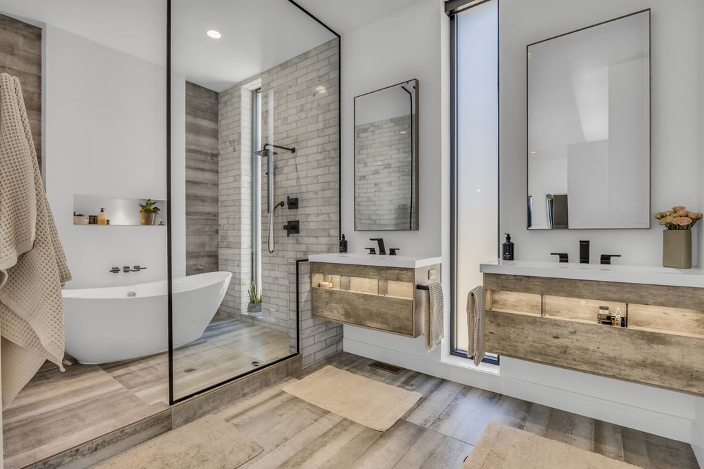 Modern bathroom featuring a freestanding tub, glass-enclosed shower, dual floating vanities with integrated lighting, and contemporary black fixtures