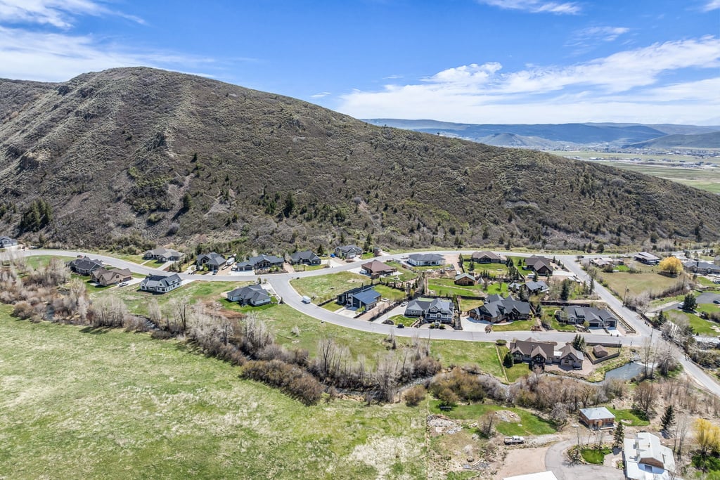 Residential neighborhood situated at the base of a verdant mountain, featuring a network of paved roads and mature landscaping