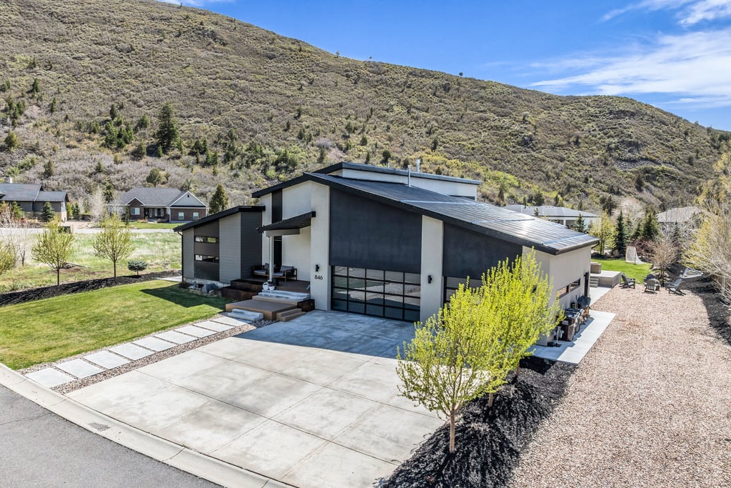 Contemporary exterior with a multi-level roofline, attached garage with glass-paneled door, concrete driveway, and a front walkway featuring rectangular pavers