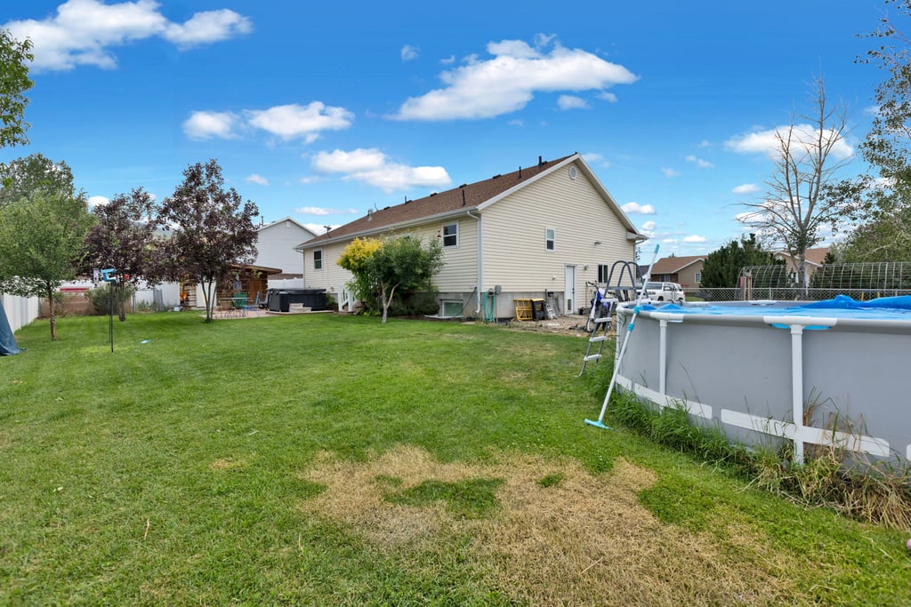 Expansive green lawn with mature trees and a white privacy fence
