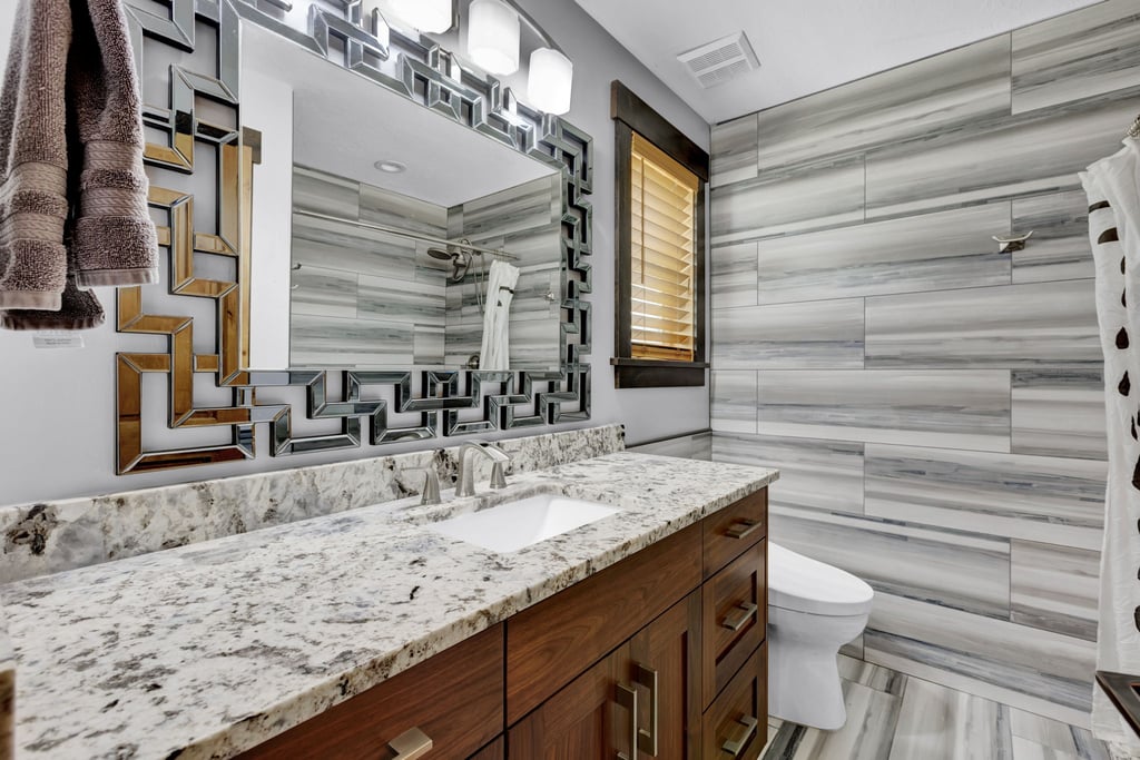 Bathroom featuring a dual vanity with a speckled countertop and undermount sinks, wood-finish cabinetry, and brushed nickel hardware