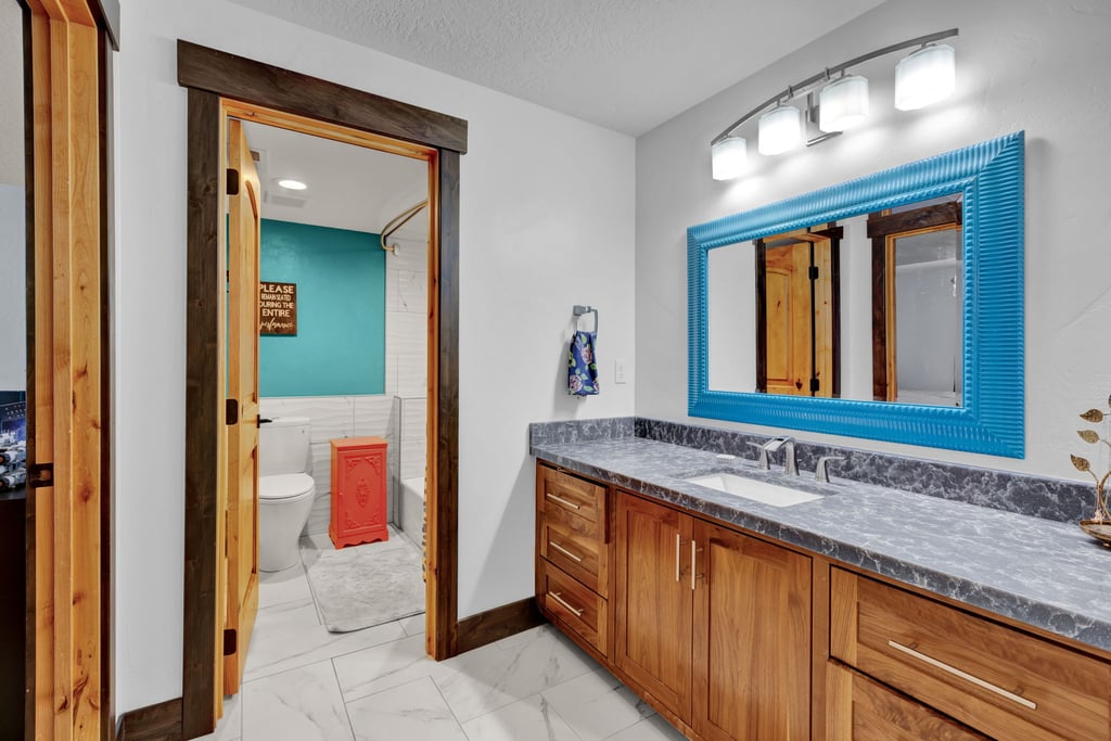 Bathroom vanity featuring wood cabinetry, a dark countertop, and an undermount sink with a chrome faucet