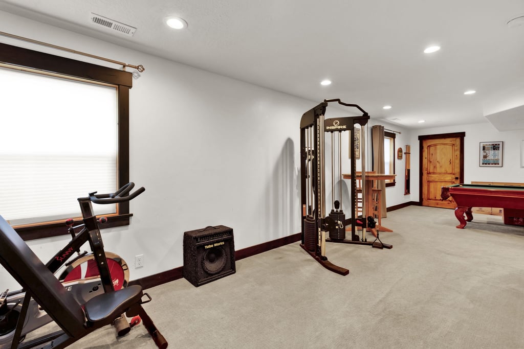 Spacious finished basement featuring recessed lighting, a window with wood trim, and a rustic wood door