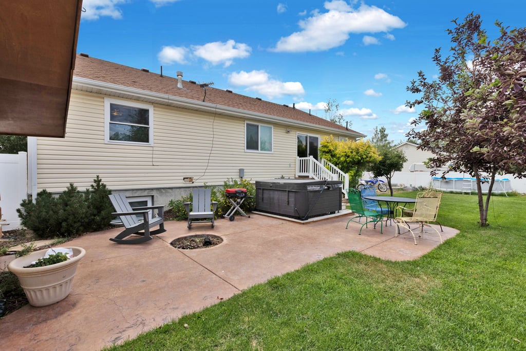 Expansive backyard featuring a stamped concrete patio, manicured lawn, mature trees, and privacy fencing