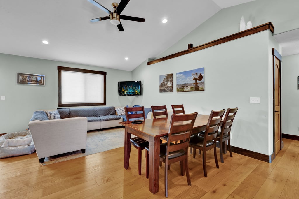 Open-concept living and dining area featuring wood-finish flooring, recessed lighting, and a vaulted ceiling