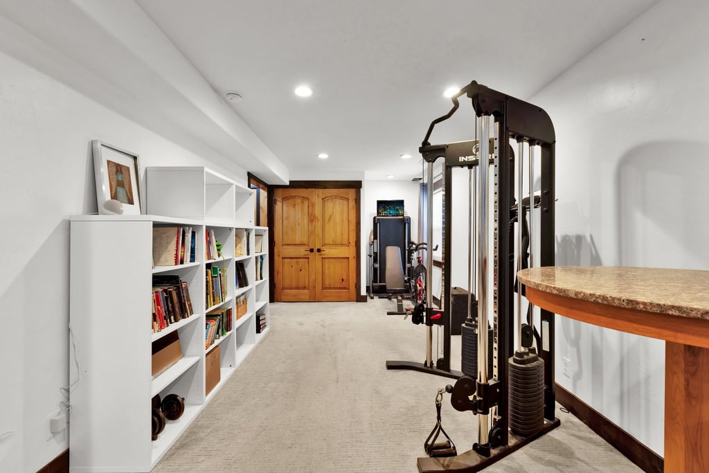 Finished lower level featuring recessed lighting, built-in shelving, plush carpeting, and warm wood double doors