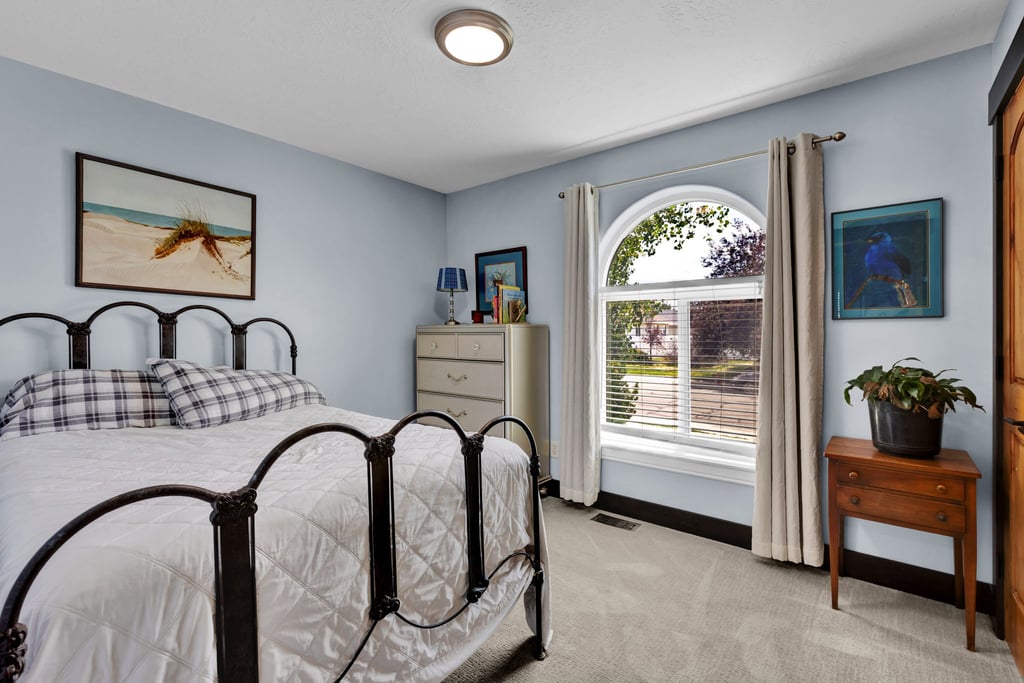 Arched window with blinds and drapes, light blue walls, and grey carpet flooring