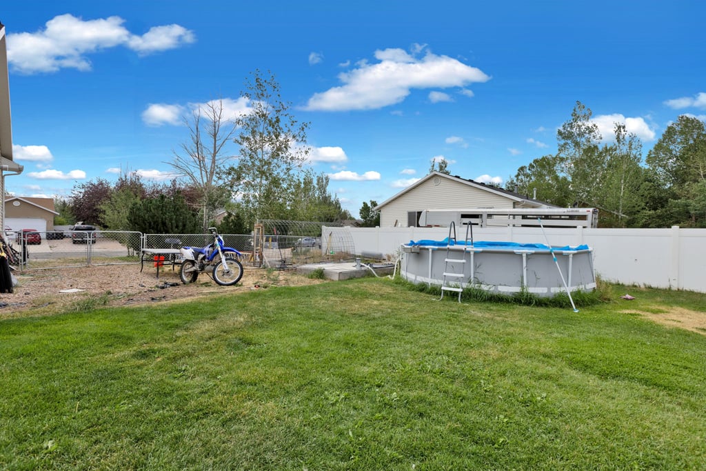 Expansive green lawn with a white privacy fence