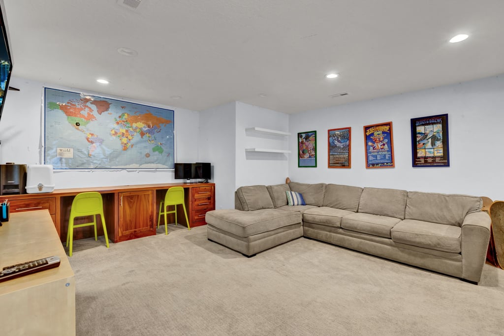 Expansive room featuring recessed lighting, plush carpet flooring, and a built-in wood-finish desk with integrated cabinetry