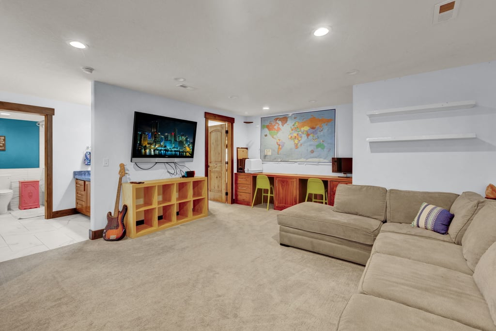 Spacious recreational room featuring recessed lighting, light-toned carpeting, and a built-in desk area with wood-finish cabinetry