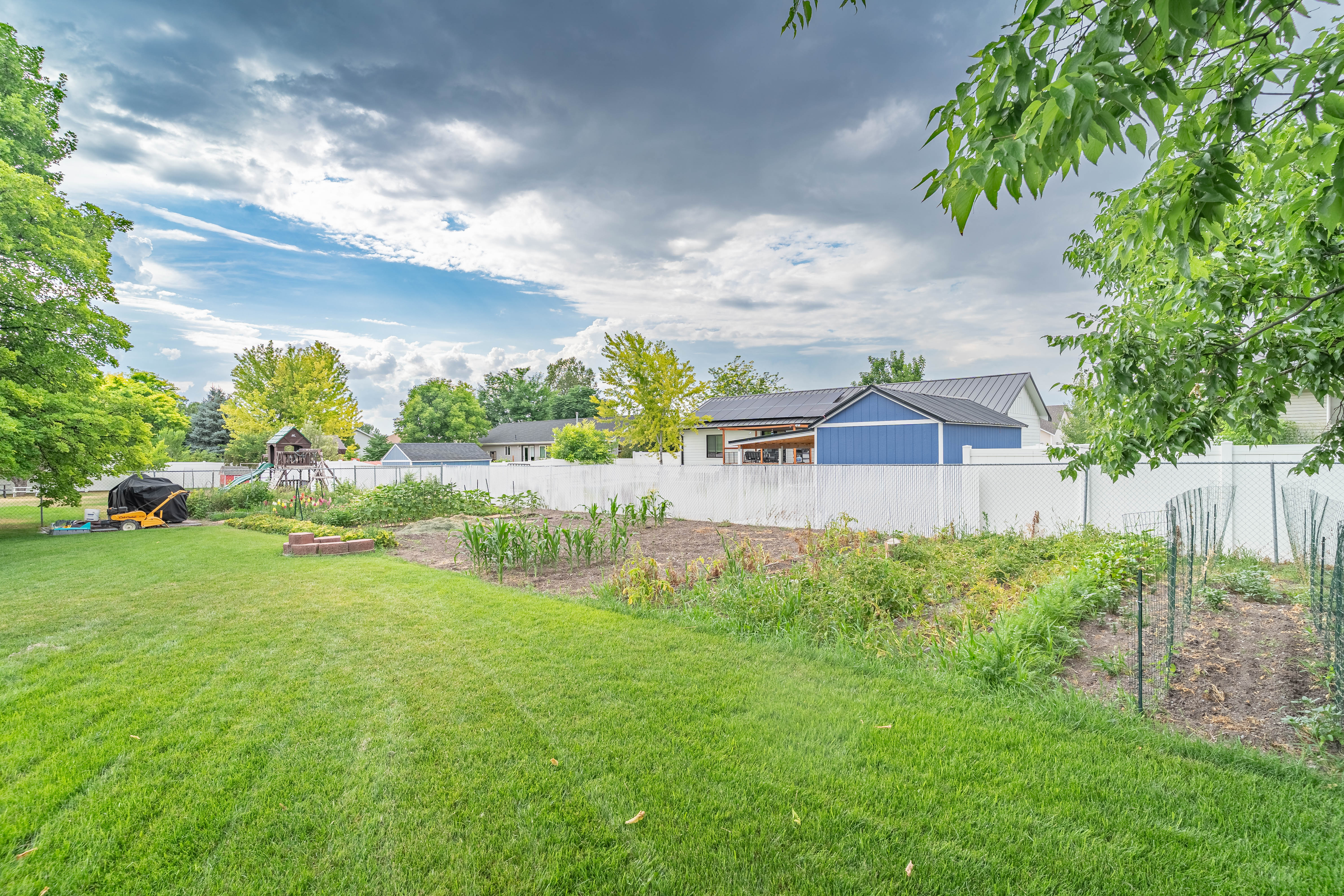 Expansive backyard featuring a manicured lawn, a dedicated garden area, and mature trees