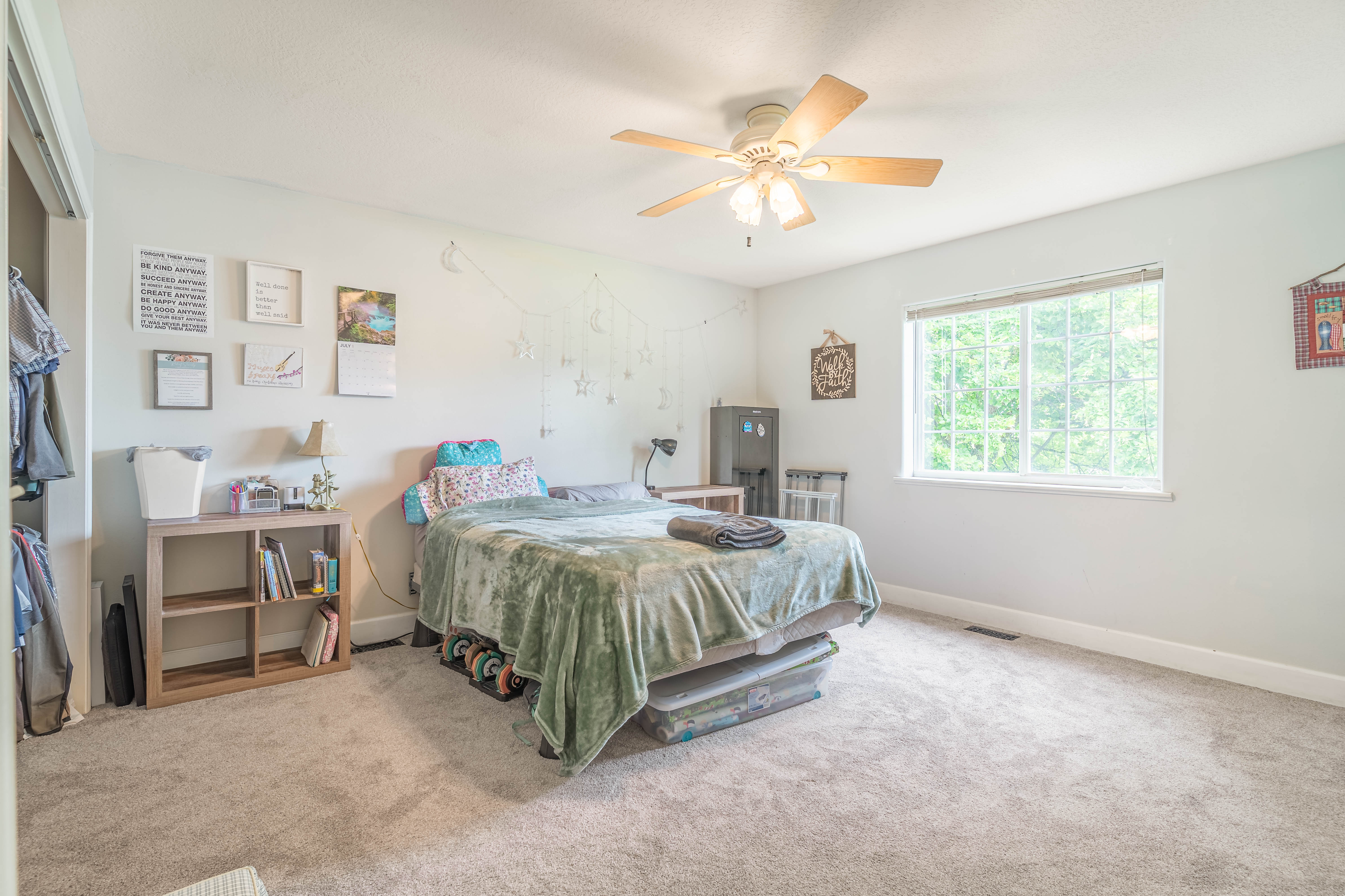 Carpeted room featuring a large window, a ceiling fan, and light-colored walls