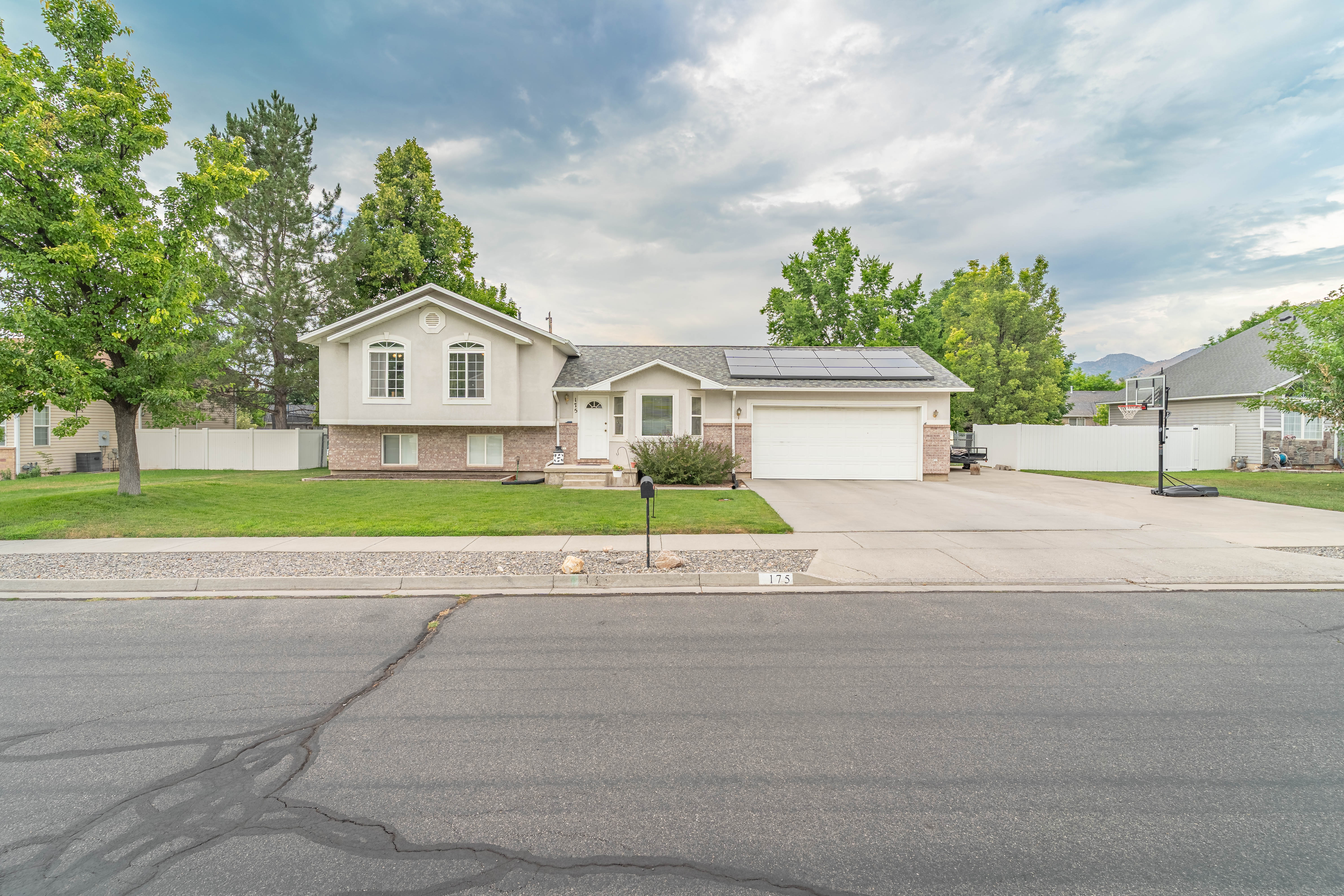 Split-level residence featuring a two-car garage, solar panels, and a concrete driveway