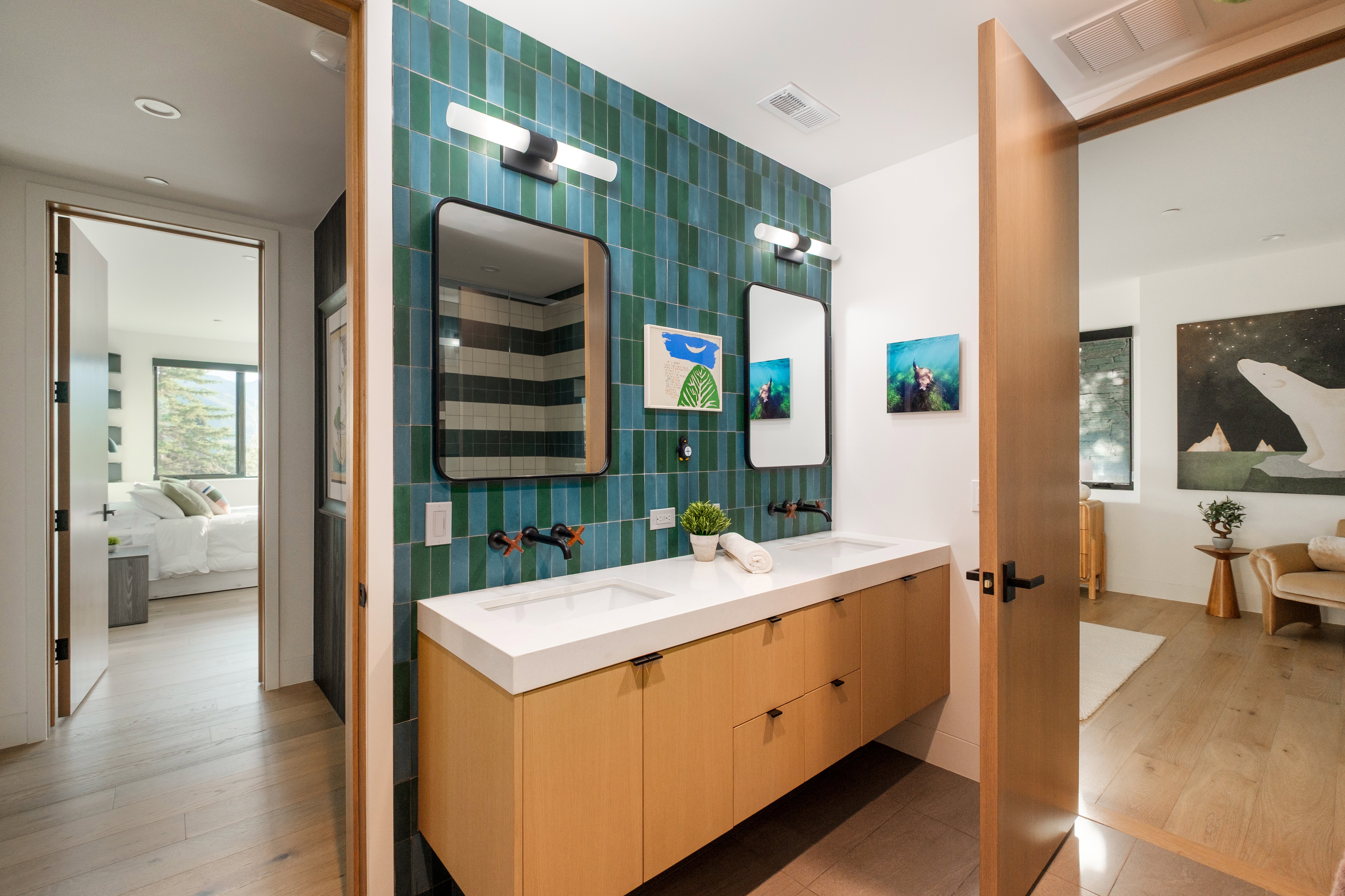Dual sink vanity featuring light wood cabinetry, white countertops, and wall-mounted black faucets