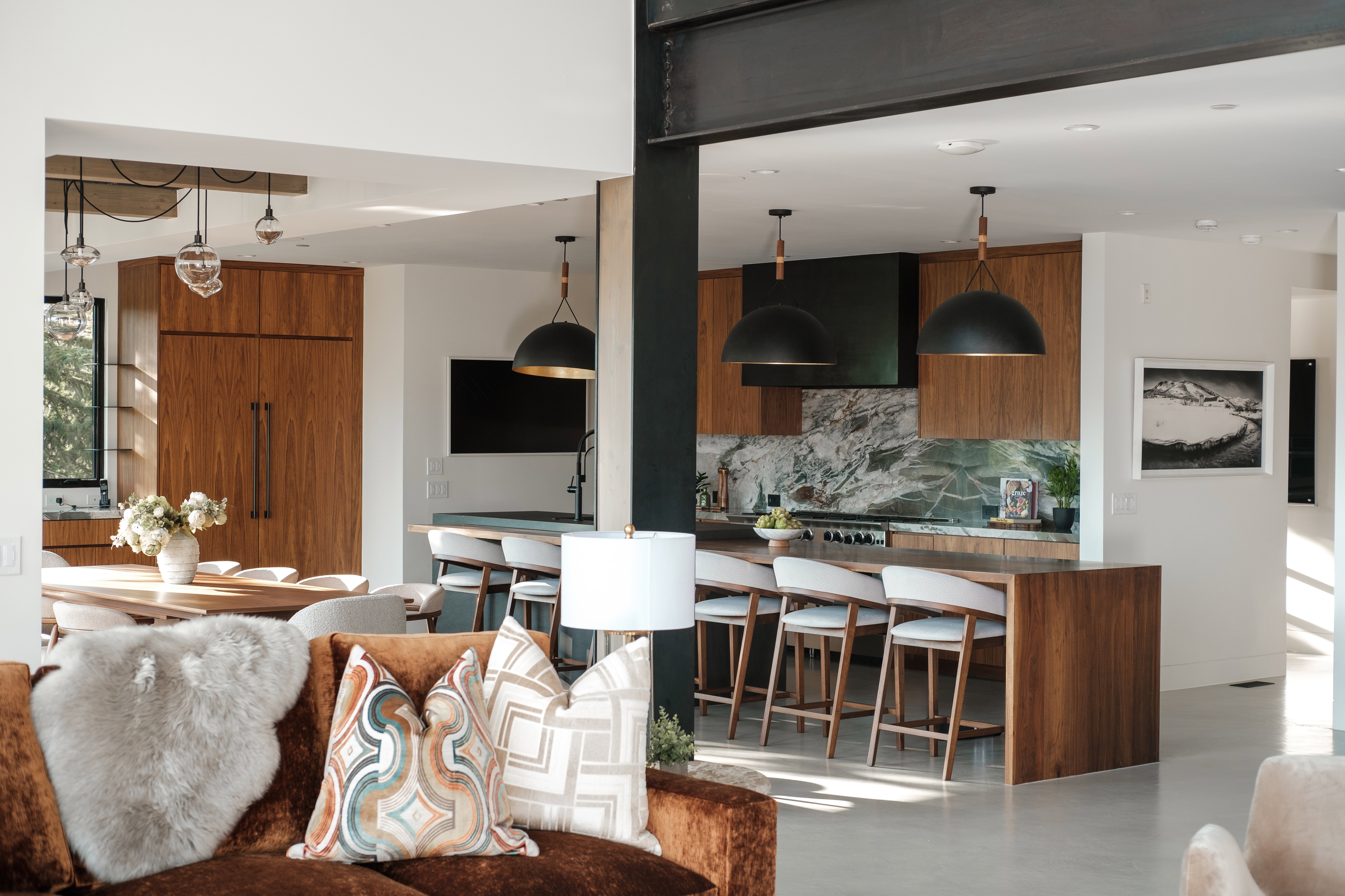 Open-concept living space featuring a gourmet kitchen with wood cabinetry, a large kitchen island with seating, a patterned stone backsplash, and recessed lighting