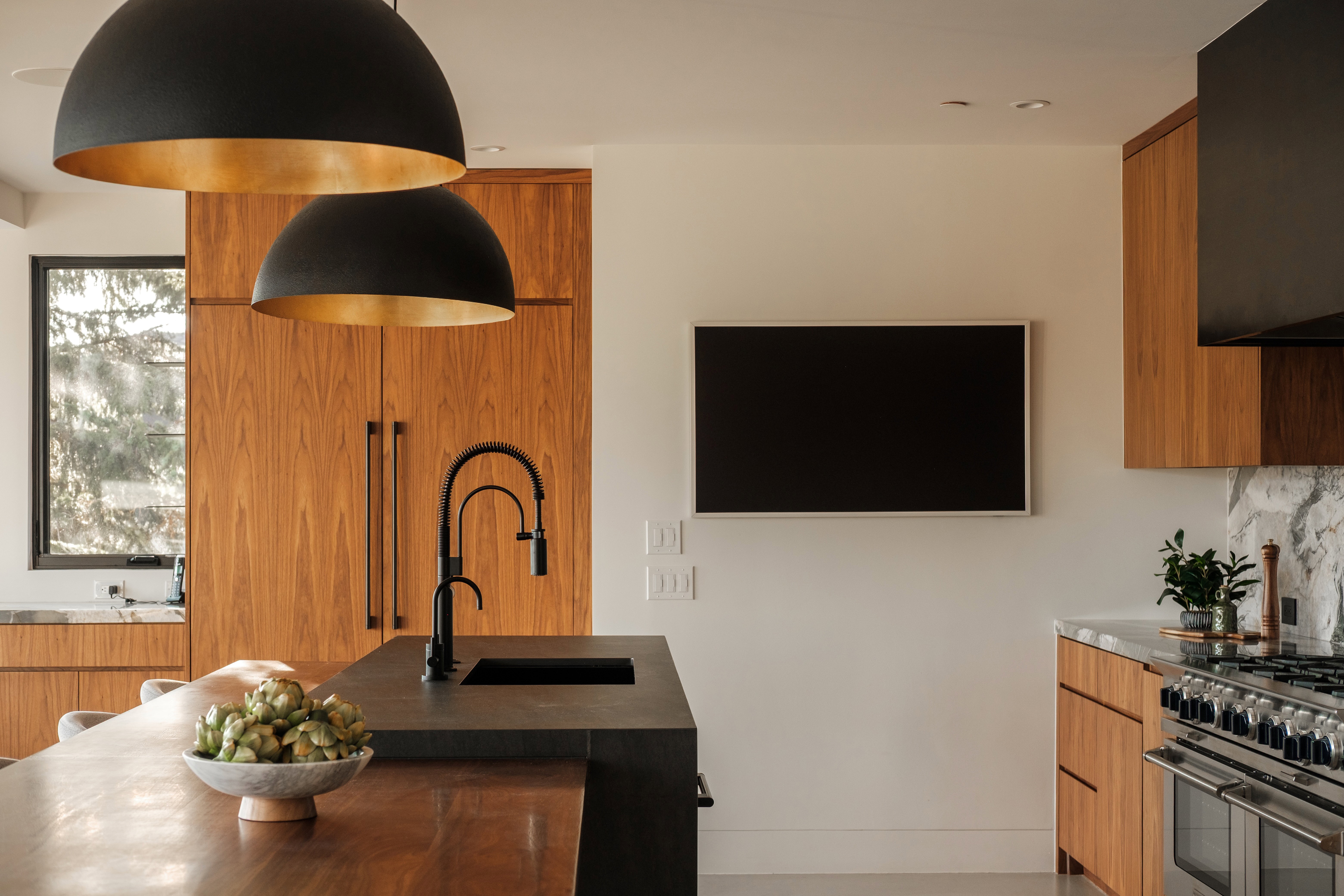 Modern kitchen featuring rich wood cabinetry and a large center island with an integrated sink and matte black faucet